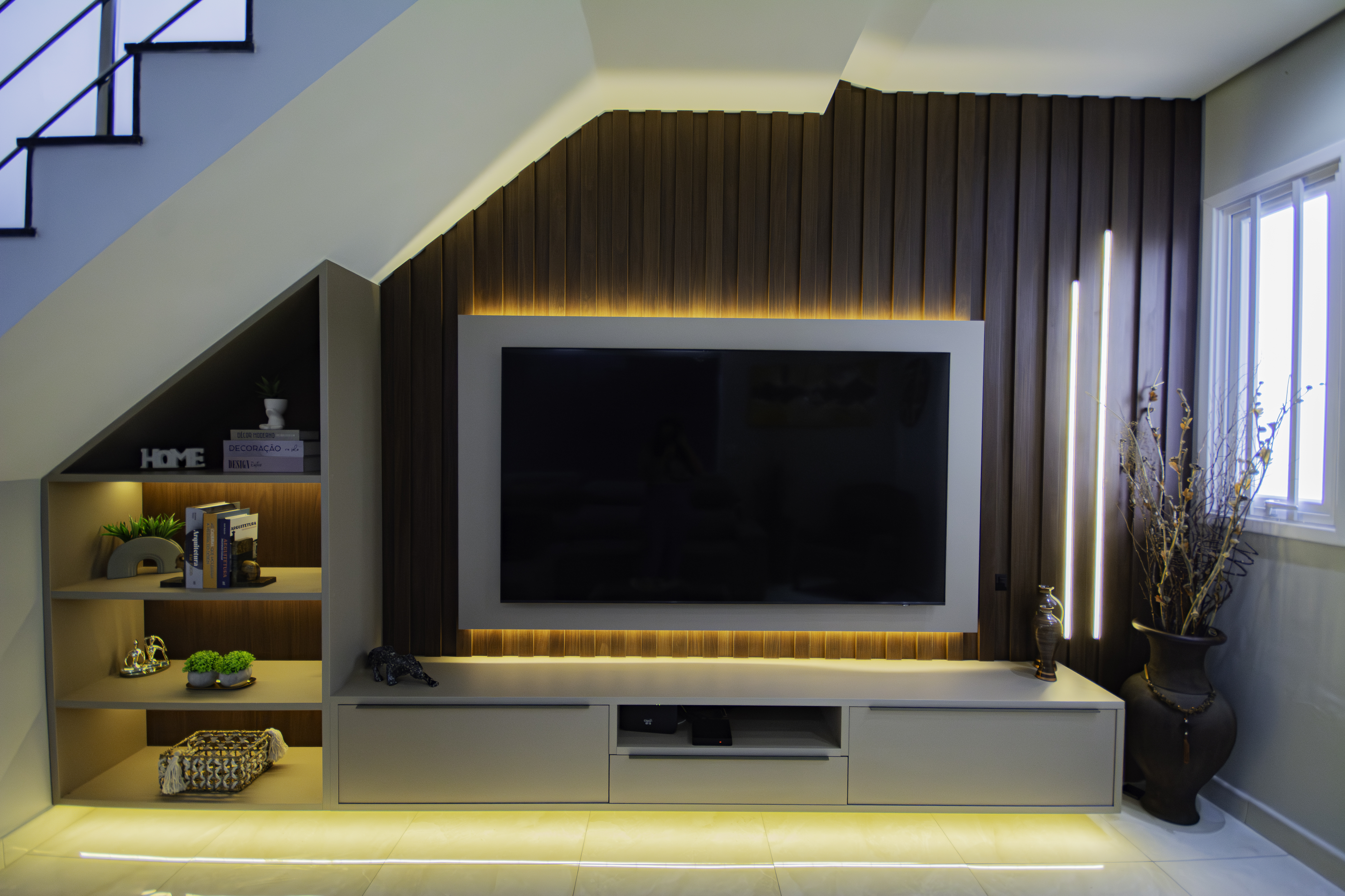 Painel de TV com nicho iluminado sob escada — projeto Tudo Novo Italínea